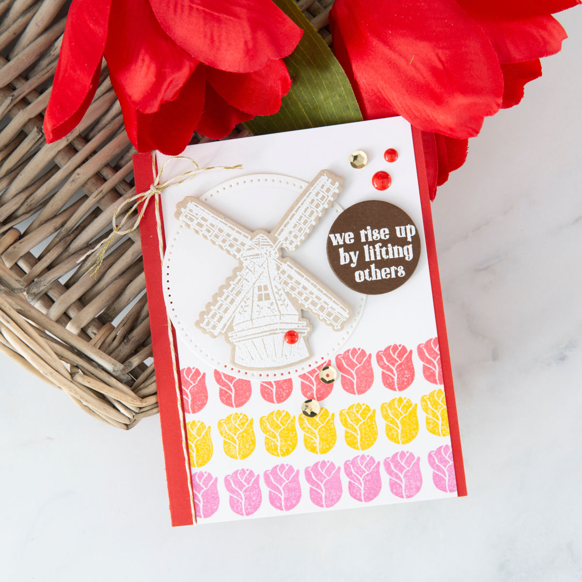 We Rise By Lifting Others crisp and bright handmade card with pink, red, and yellow stamped tulips and beautiful Dutch windmill embossed in white. #funstampersjourney #cardmaking