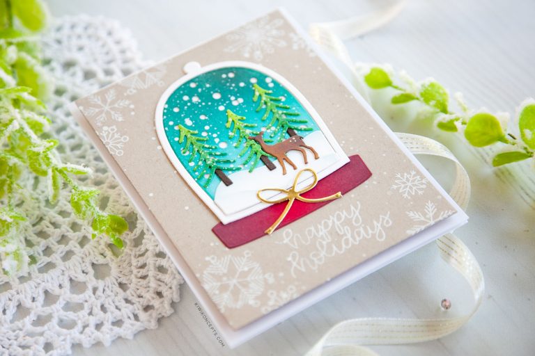Spellbinders Holiday 2019 Inspiration | Clean & Simple Christmas Cards with Keeway Tsao. Keeway says: "This card showcases the Shapeabilities Santa’s Workshop dies. This die creates a beautiful little scene within a snow globe. I started by die cutting the snow globe frame and backing which was then ink blended with Peacock Feathers and Tumbled Glass distress oxide inks."